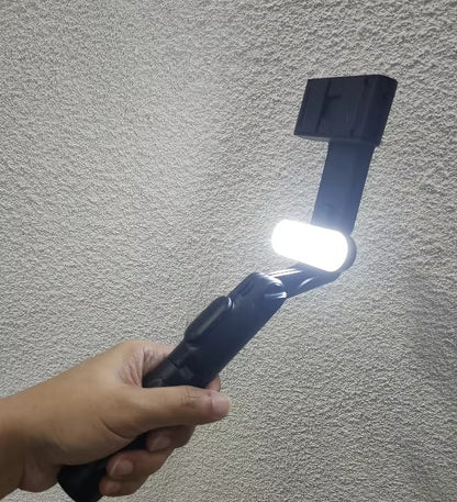 Hand holding a flashlight against a textured gray wall